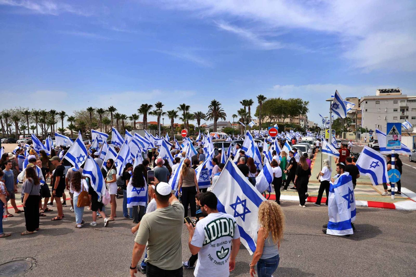 בני נוער ומבוגרים נושאים את דגלי ישראל ומנופפים בהם לאורך השיירה