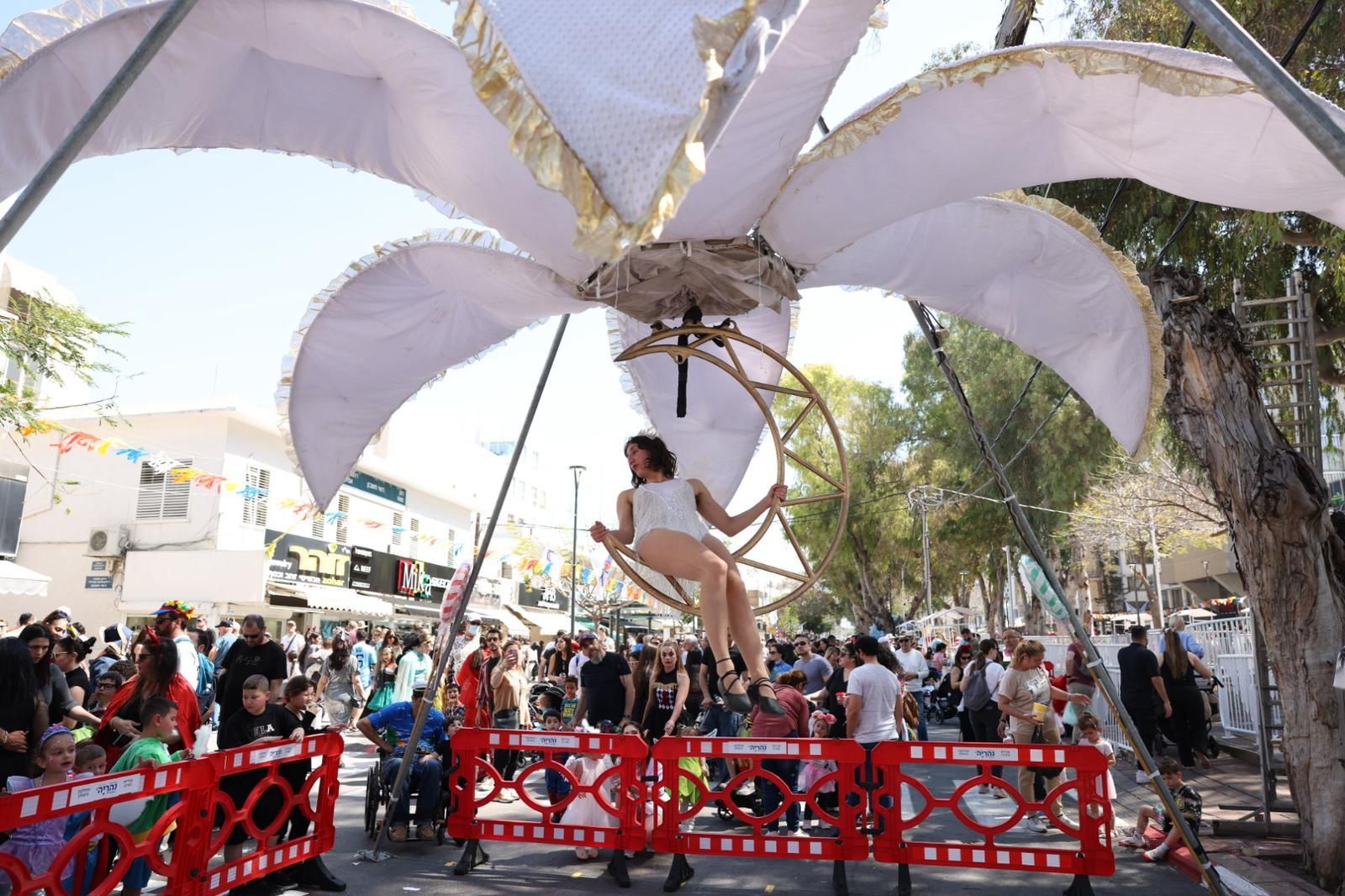 מיצג של אישה מחופשת יושבת על מתלה בצורת ירח בתוך פרח נפתח